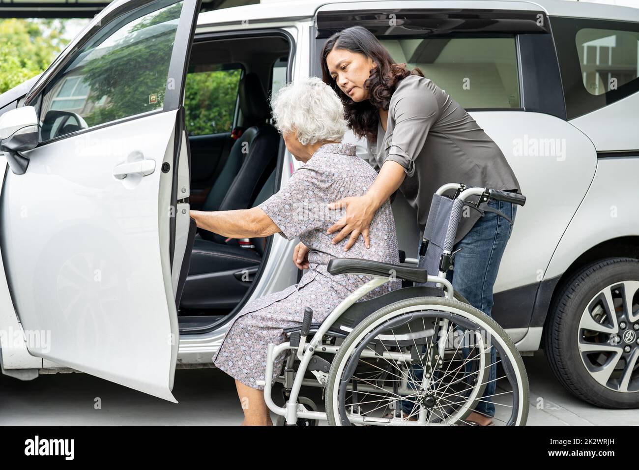 Aide-soignant fille aider et soutenir asiatique senior ou âgée vieille femme patiente préparer obtenir à sa voiture. Banque D'Images