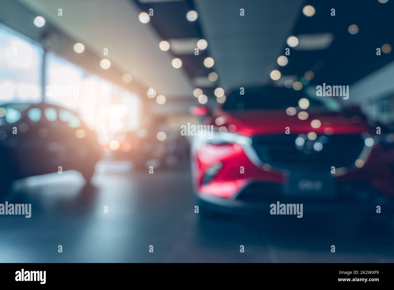 Photo floue voiture rouge neuve garée dans la salle d'exposition. Bureau de la concession automobile. Voiture garée avec soin dans la salle d'exposition. Voiture pour la vente et la location d'affaires. Marché de location d'automobiles. Véhicule électrique. Industrie automobile. Banque D'Images