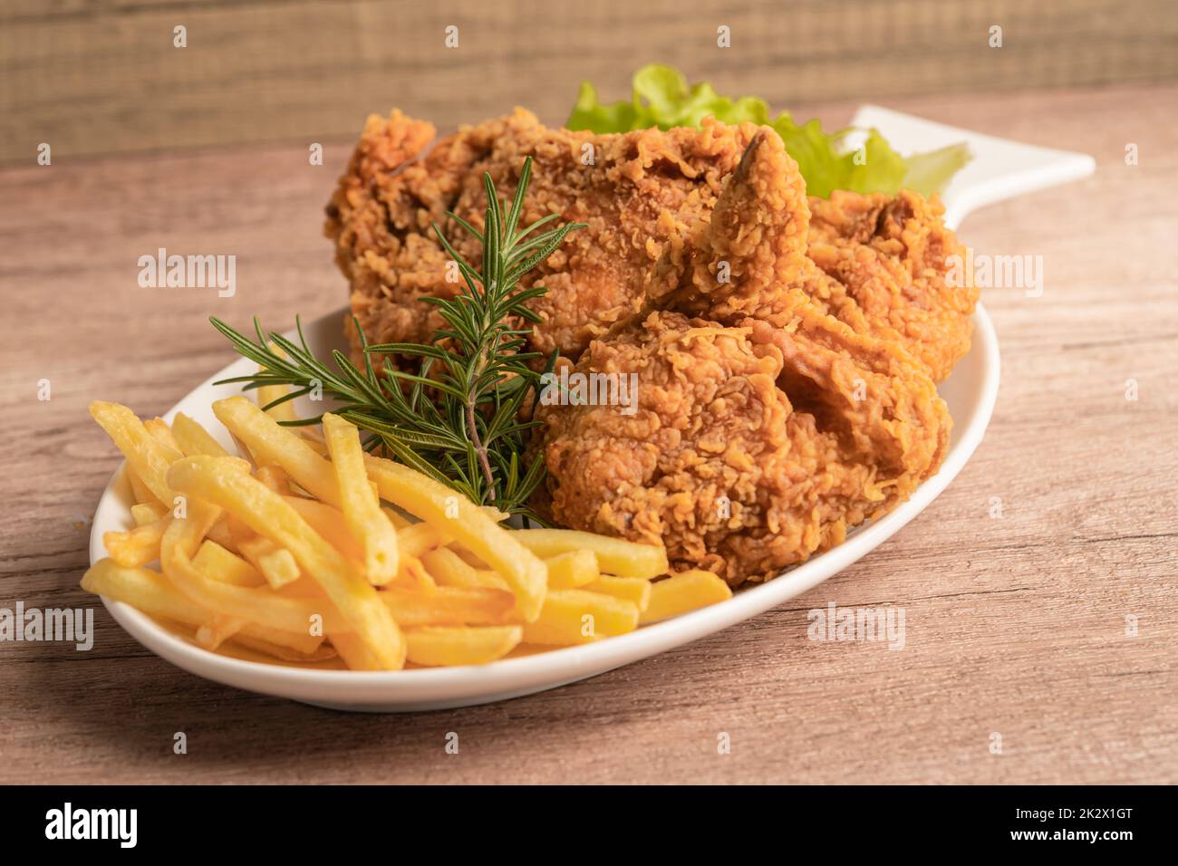 Poulet frit et croustilles avec feuille de romarin, nourriture Junk à haute teneur en calories servie sur une assiette blanche Banque D'Images