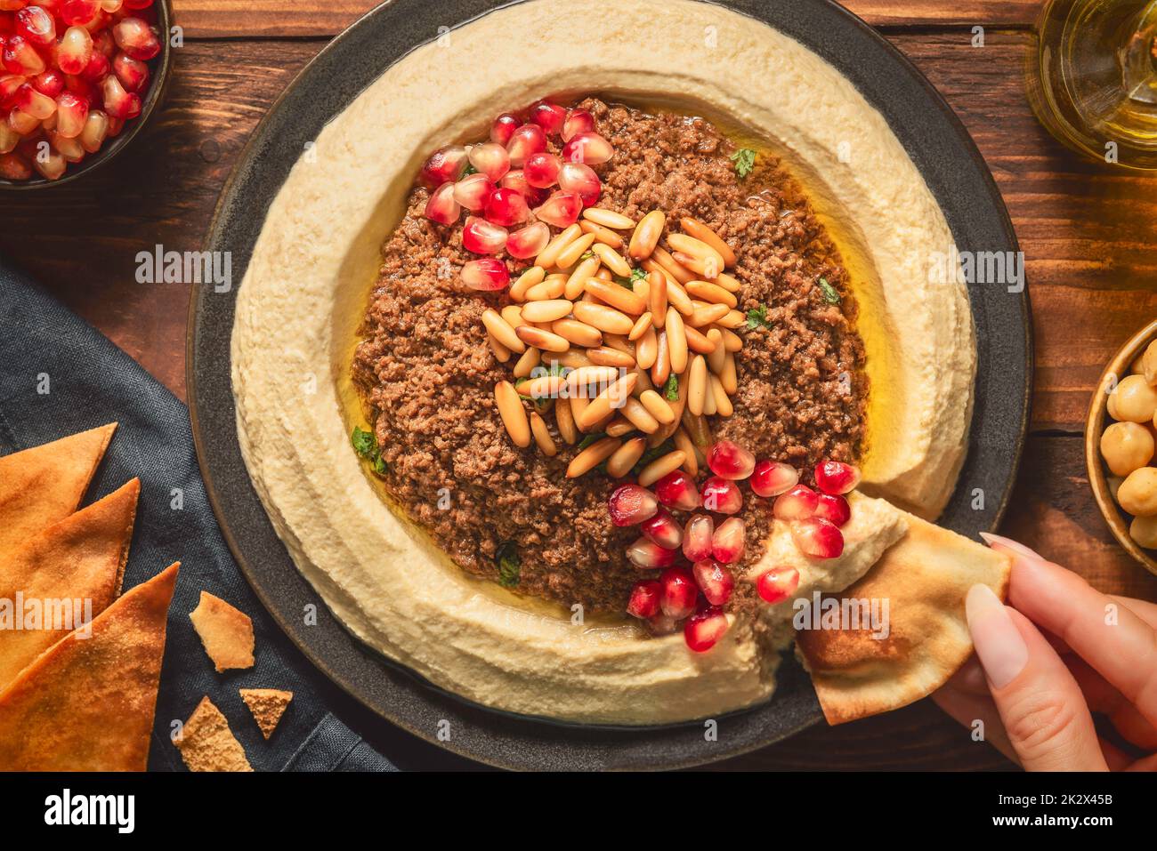 Cuisine arabe ; trempette crémeuse traditionnelle à l'houmous avec bœuf haché. Garnie d'huile d'olive, de graines de grenade fraîches, de pignons de pin rôtis et de persil. Banque D'Images
