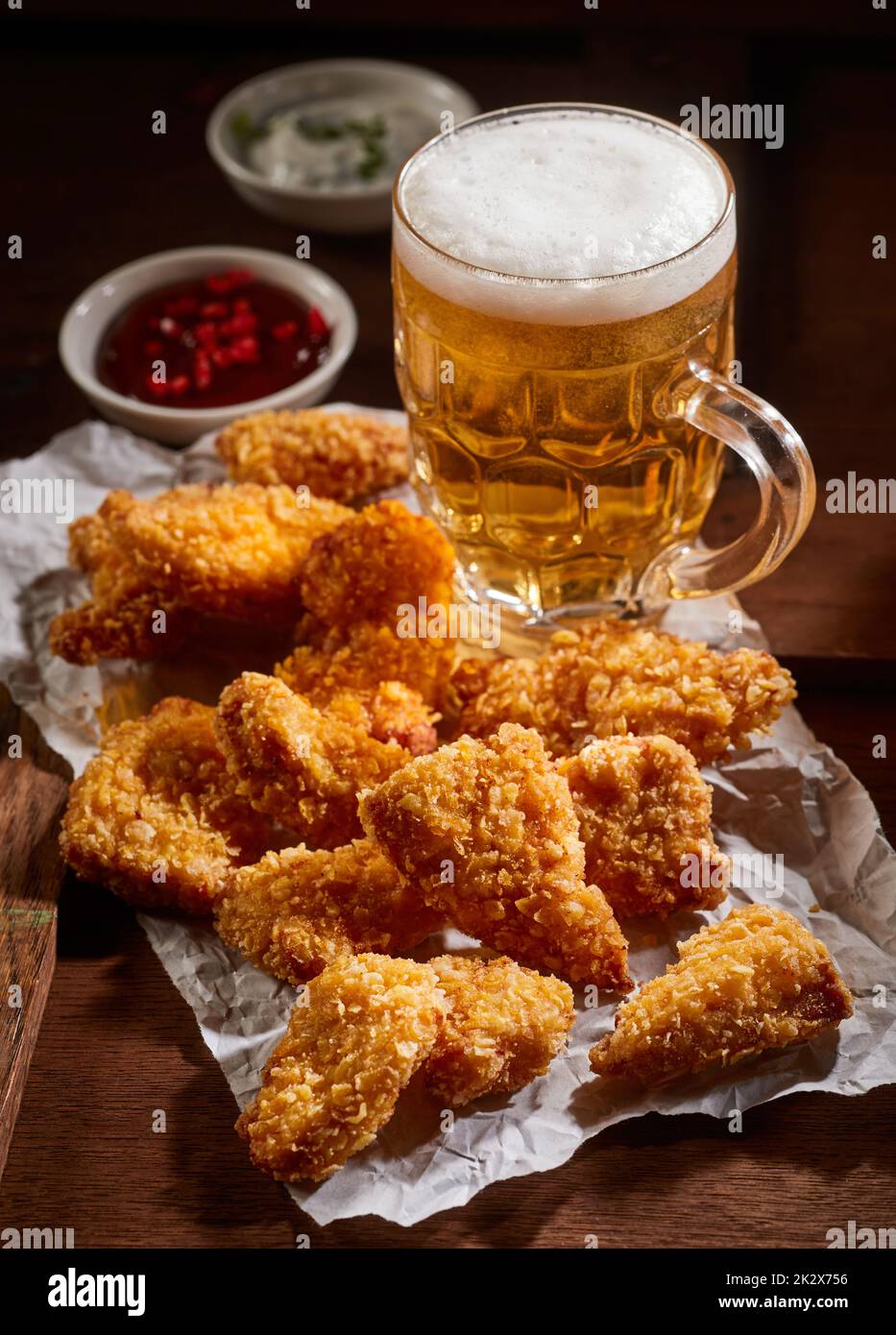 Nuggets de poulet près d'une tasse à bière Banque D'Images
