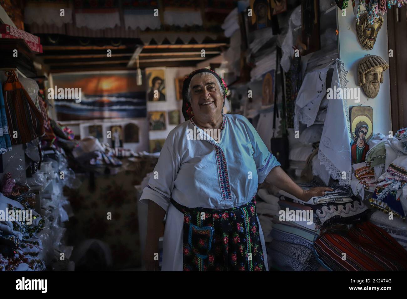 Mme Rigopoula à sa boutique avec des textiles locaux tissés à la main, des scarfs traditionnels et des mini-costumes traditionnels pour poupées, village Olympos, île Karpathos. Karpathos est la deuxième plus grande île du complexe grec Dodécanèse, dans le sud-est de la mer Égée. L'île de Karpathos conserve toujours son mode de vie traditionnel, comme le village 'Olympos', où les autochtones portent encore les costumes traditionnels. Banque D'Images