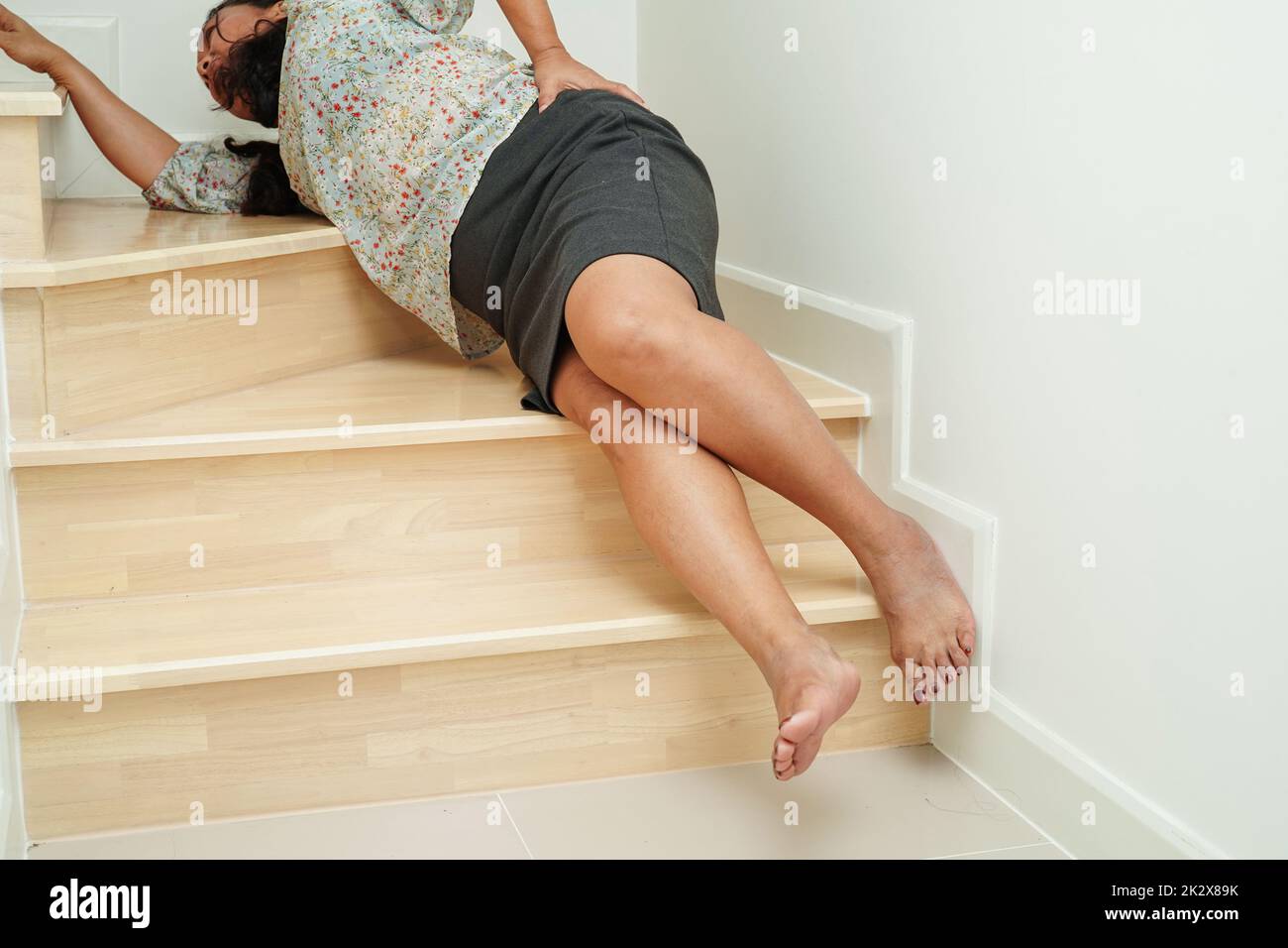 Femme asiatique blessée de tomber sur des surfaces glissantes escaliers à la maison. Banque D'Images