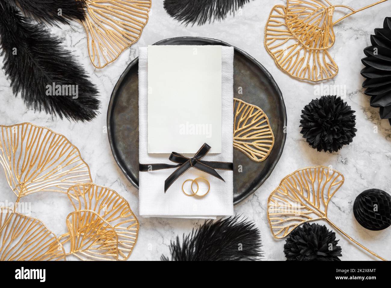 Table de mariage noire et dorée avec une carte vierge et des anneaux vue du dessus, maquette Banque D'Images