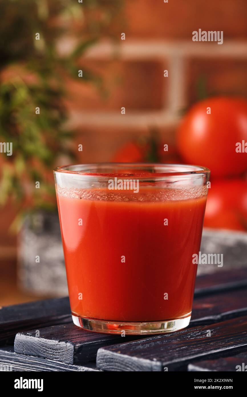 Délicieux jus de tomates dans un verre avec des tomates rouges mûres. Banque D'Images