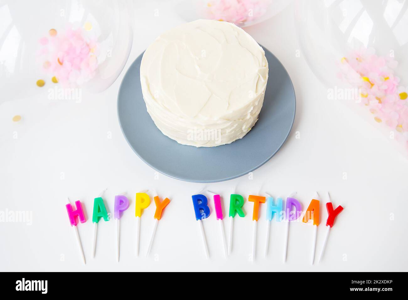 Bougies colorées avec lettrage joyeux anniversaire isolées sur fond blanc avec confetti et gâteau bento. Concept de vacances et de surprise. Banque D'Images