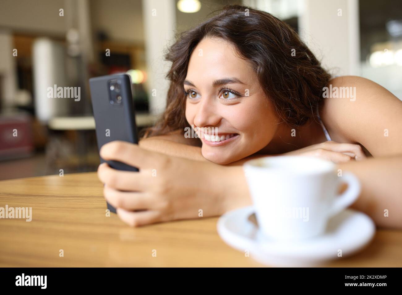 Une femme heureuse qui se présente au téléphone portable dans un café Banque D'Images
