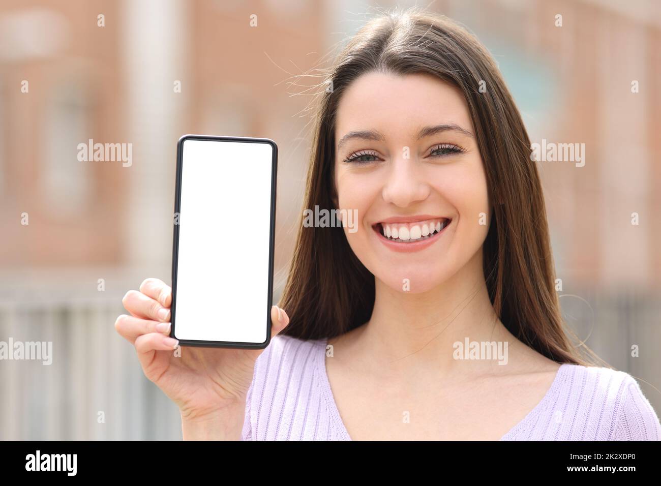 Joyeux adolescent montrant le téléphone intelligent écran vide dans la rue Banque D'Images