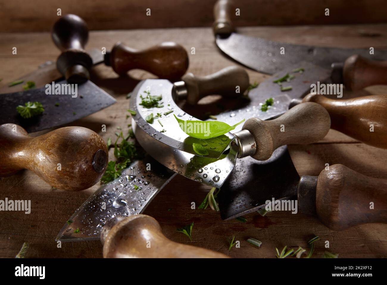 Ensemble de couteaux de mezzaluna à l'ancienne recouverts de légumes verts hachés Banque D'Images