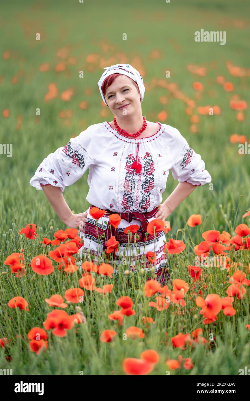 Femme en robe nationale ukrainienne sur un champ de pavot à fleurs Banque D'Images