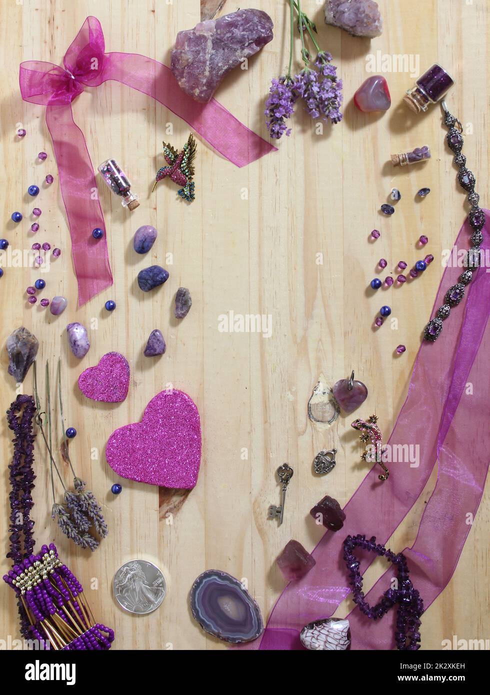 Bijoux violet et rose avec coeurs à paillettes et pierres améthystes sur fond en bois Banque D'Images