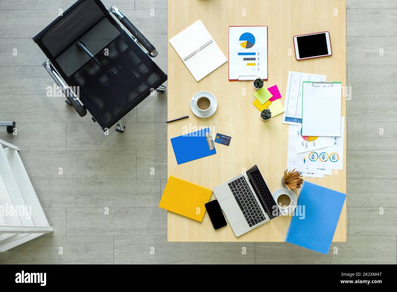 Vue en grand angle du bureau. Ordinateur portable, tablette, téléphone portable, carte de crédit, café, fixe, document, graphique, carte sont sur table en bois. Banque D'Images