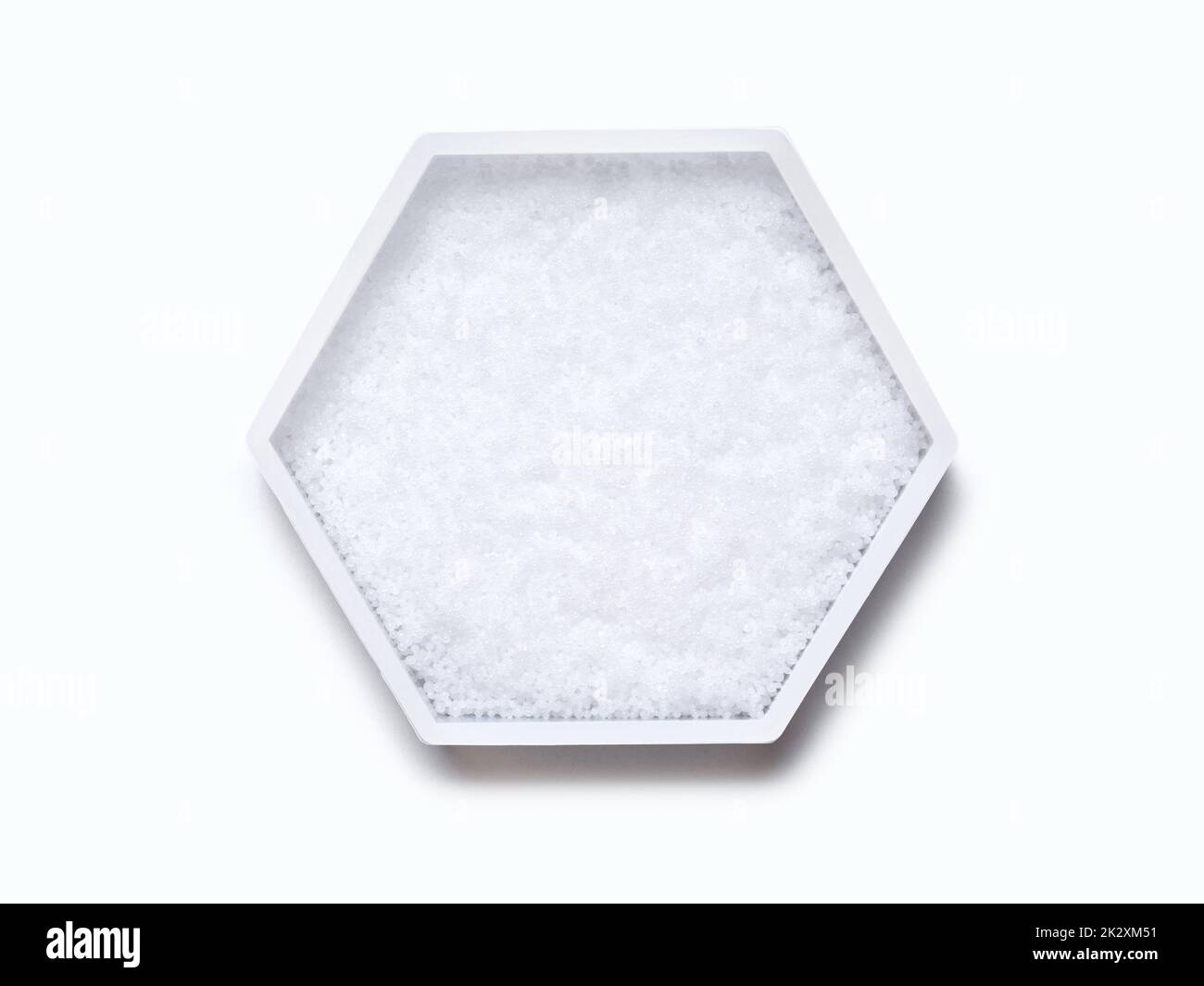 Pastilles d'hydroxyde de sodium en conteneur hexagonal de forme moléculaire sur fond blanc. Vue de dessus Banque D'Images