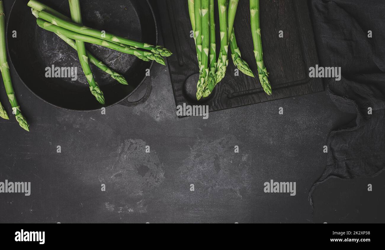 Asperges vertes fraîches dans une casserole ronde en fonte sur une table noire Banque D'Images