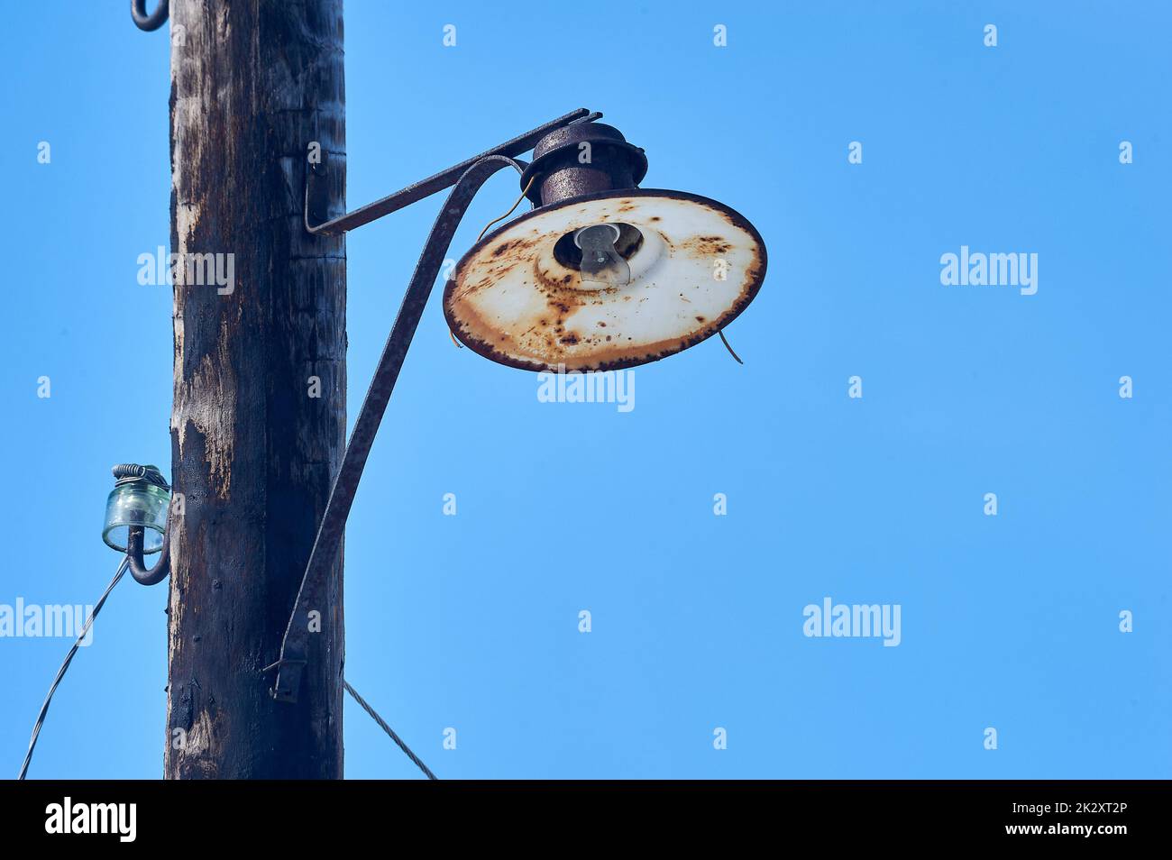 une vieille lanterne est suspendue sur un poteau en bois avec une ampoule cassée Banque D'Images