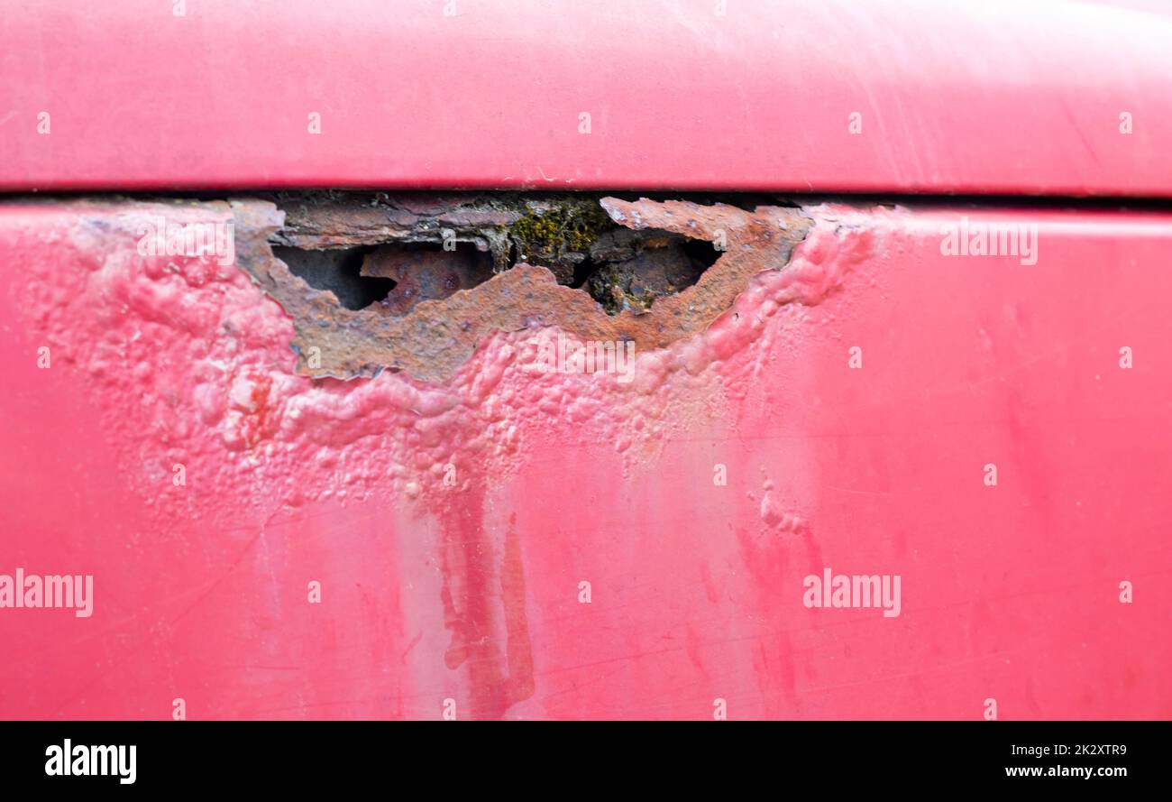 Aile rouillée. Corrosion de la carrosserie d'une vieille voiture rouge après l'hiver. Influence des réactifs en hiver sur le corps d'un véhicule non protégé. Dommages du côté gauche. Banque D'Images