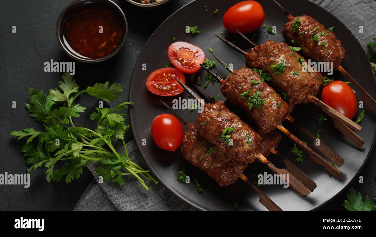 Le kebab shish est un repas populaire composé de cubes de viande brodés et grillés. Kebab de bœuf rôti sur une brochette de bois aux épices, aux herbes et aux tomates Banque D'Images