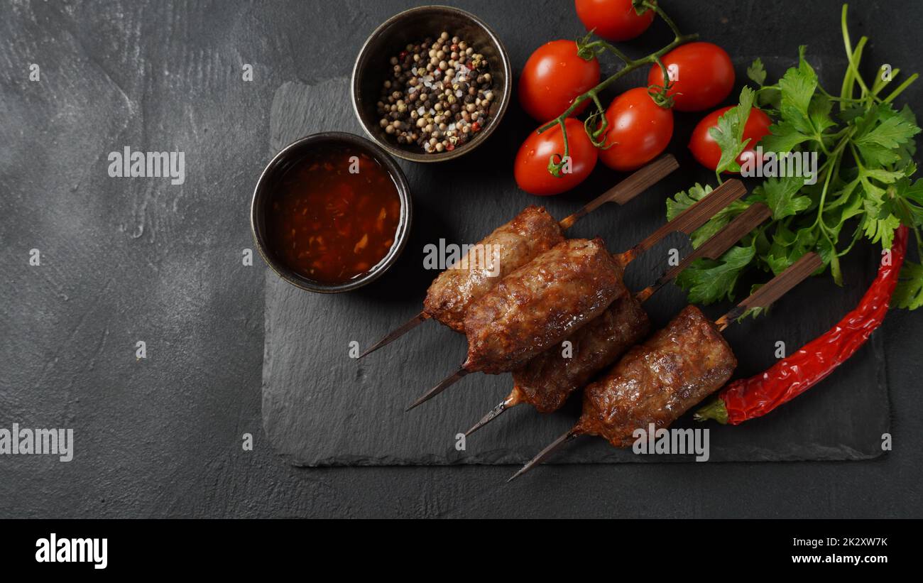 Le kebab shish est un repas populaire composé de cubes de viande brodés et grillés. Kebab de bœuf rôti sur une brochette de bois aux épices, aux herbes et aux tomates Banque D'Images