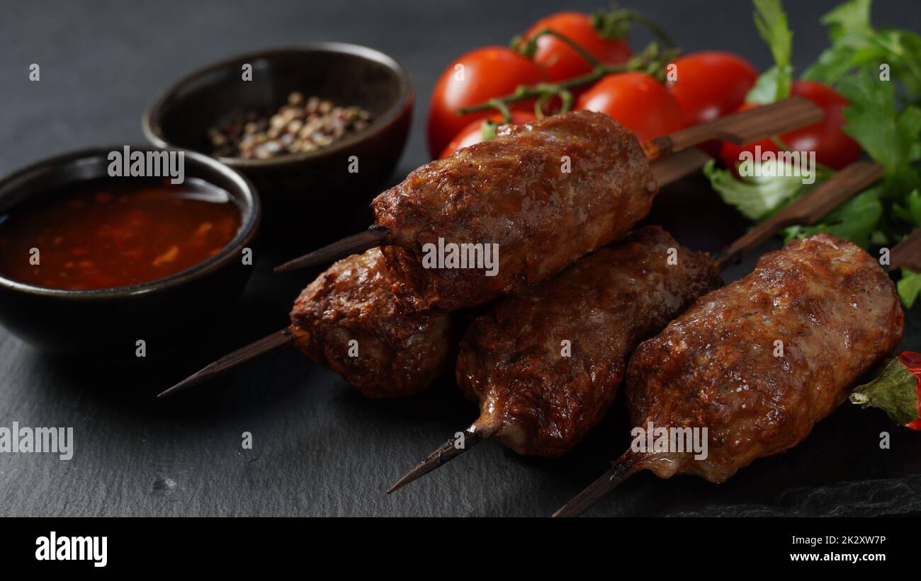 Le kebab shish est un repas populaire composé de cubes de viande brodés et grillés. Kebab de bœuf rôti sur une brochette de bois aux épices, aux herbes et aux tomates Banque D'Images