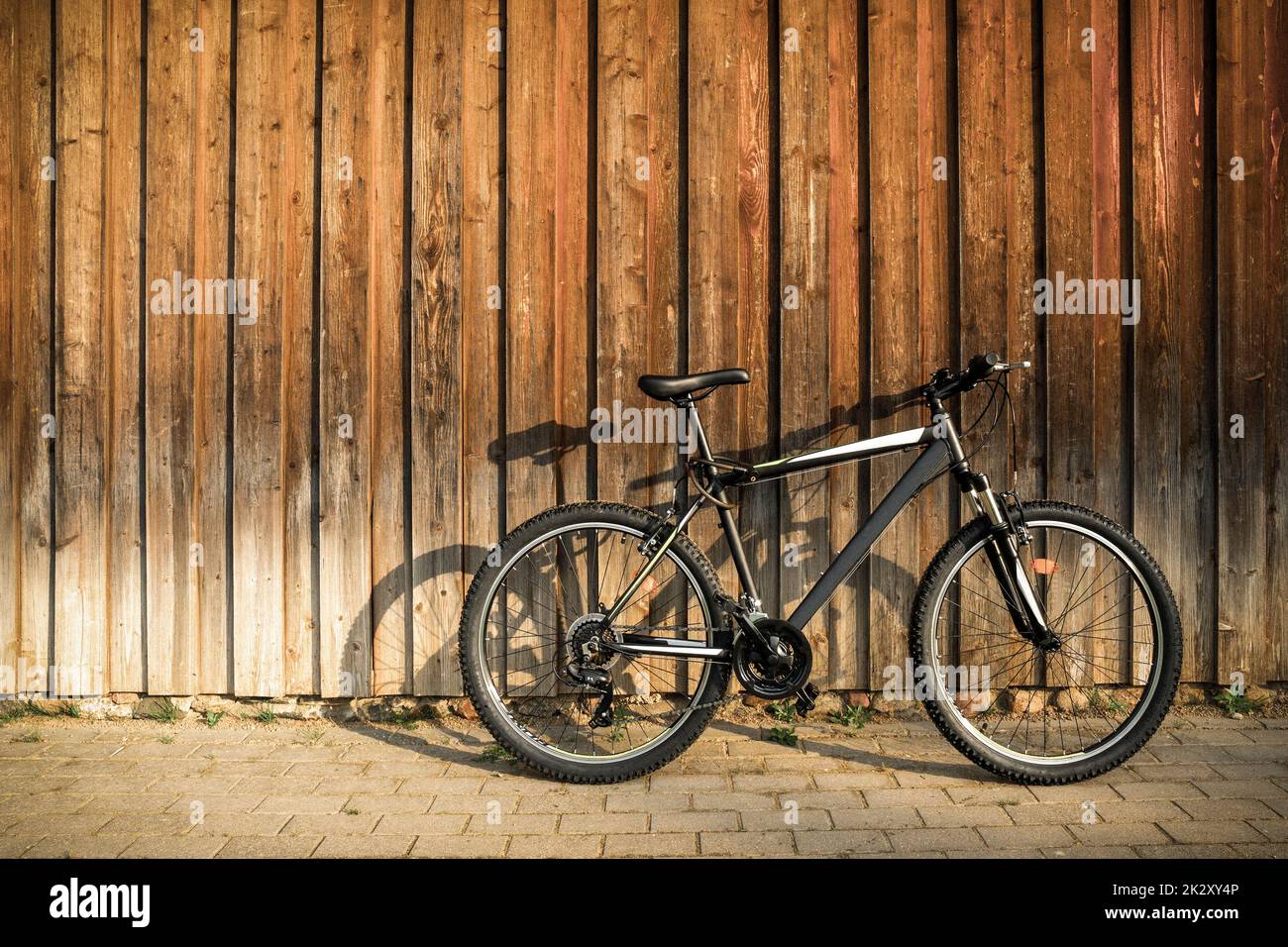 Vélo de montagne sport moderne appuyé contre un mur en bois brun Banque D'Images