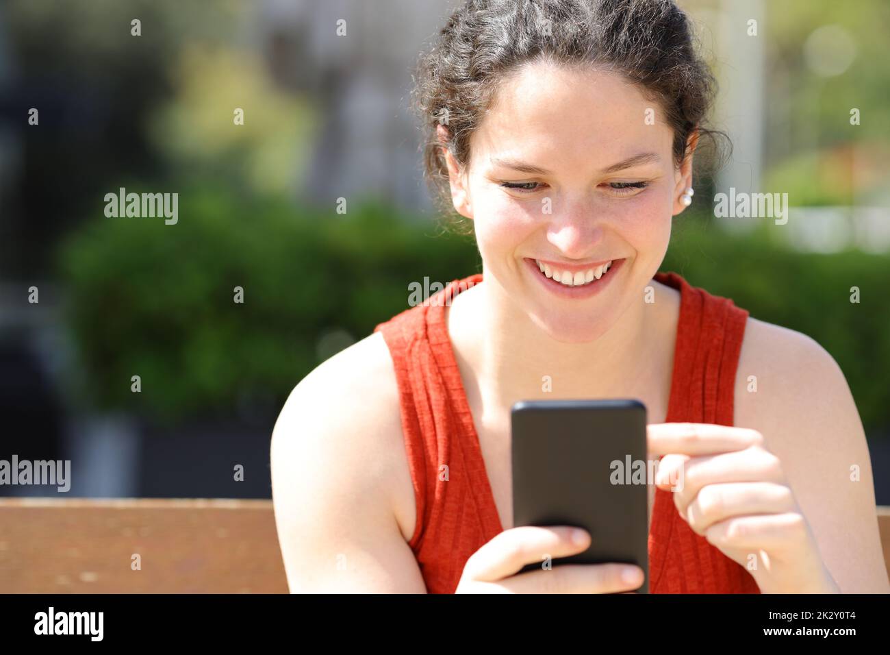 Vue avant d'une femme utilisant un téléphone cellulaire dans un parc Banque D'Images