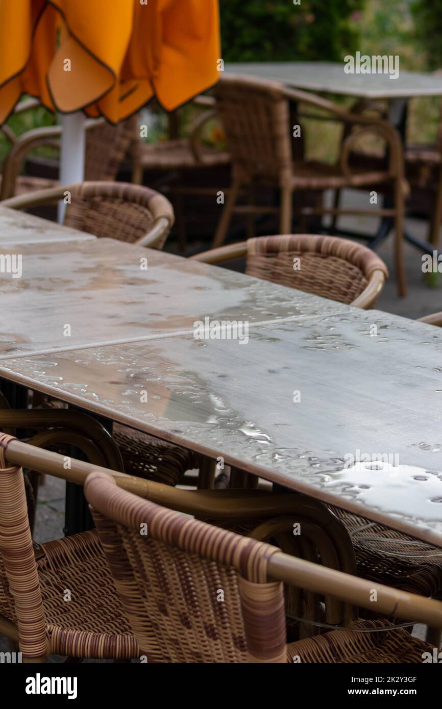 Table vide et chaises vides du restaurant d'été ou du café en plein air en été, par temps pluvieux, avec des gouttes de pluie et pas de clients, pas de revenu sur les sièges en terrasse pendant l'été pluvieux dans les restaurants à impact de confinement pandémique Banque D'Images