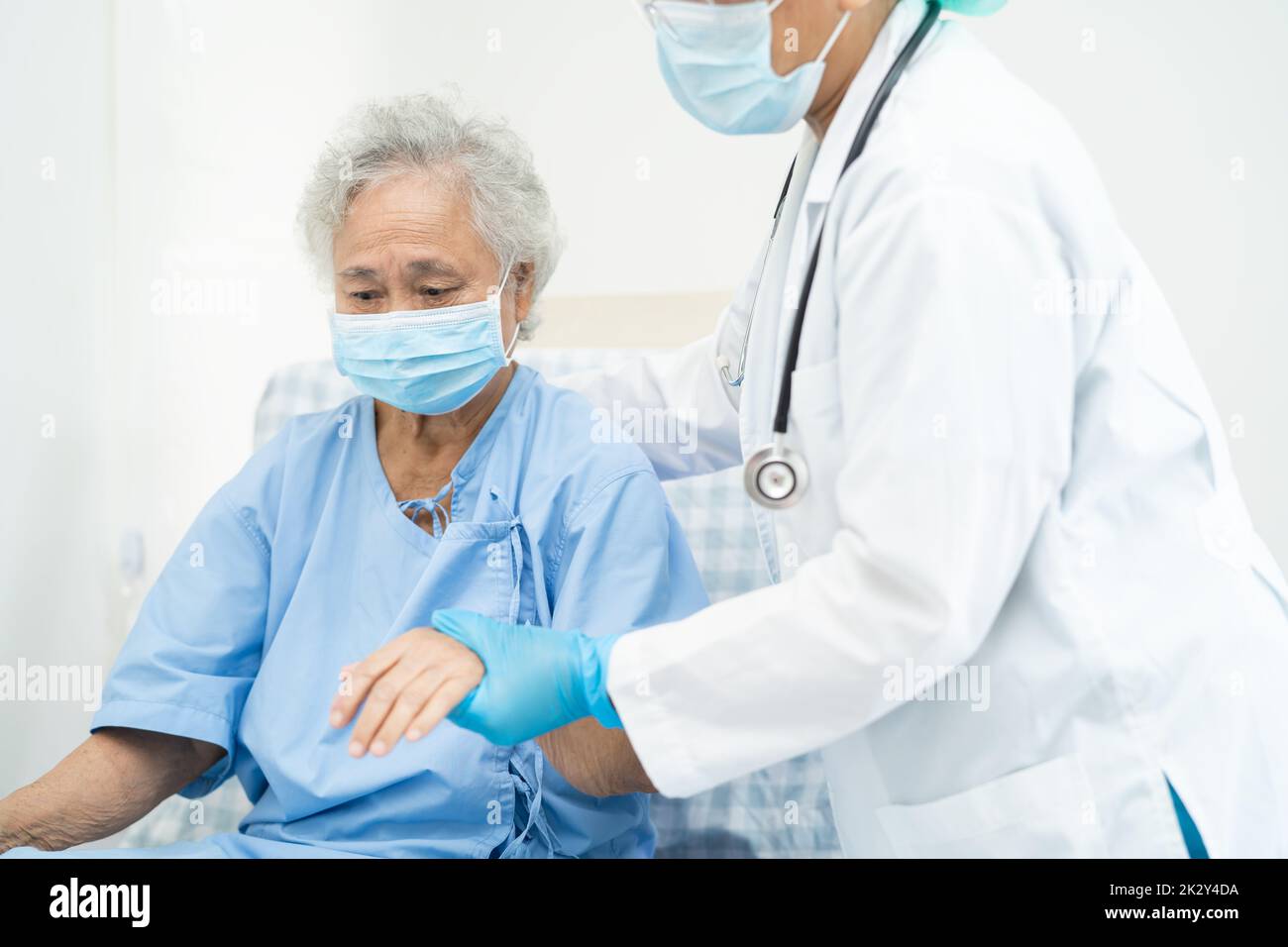 Aide médicale asiatique senior ou âgée femme âgée patient portant un masque facial à l'hôpital pour protéger l'infection de sécurité et tuer le coronavirus Covid-19. Banque D'Images