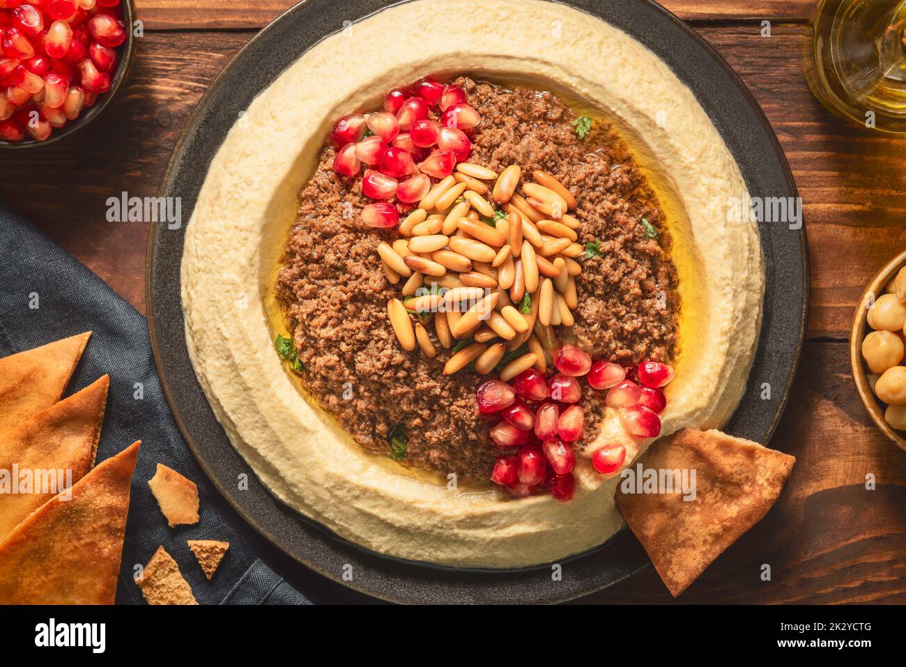 Cuisine arabe ; trempette crémeuse traditionnelle à l'houmous avec bœuf haché. Garnie d'huile d'olive, de graines de grenade fraîches, de pignons de pin rôtis et de persil. Banque D'Images