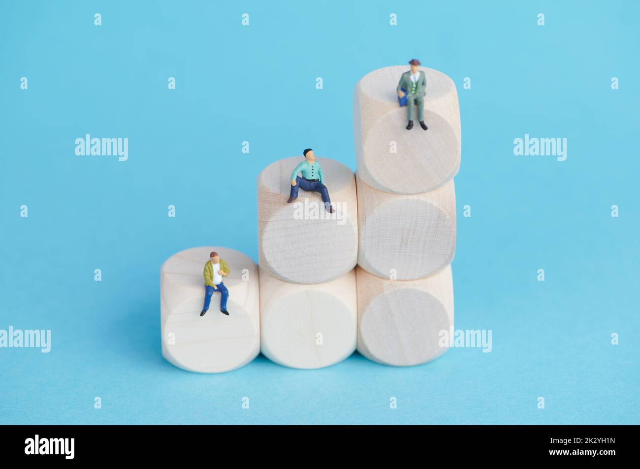 trois hommes sont assis sur des blocs de bois montant sur fond bleu Banque D'Images