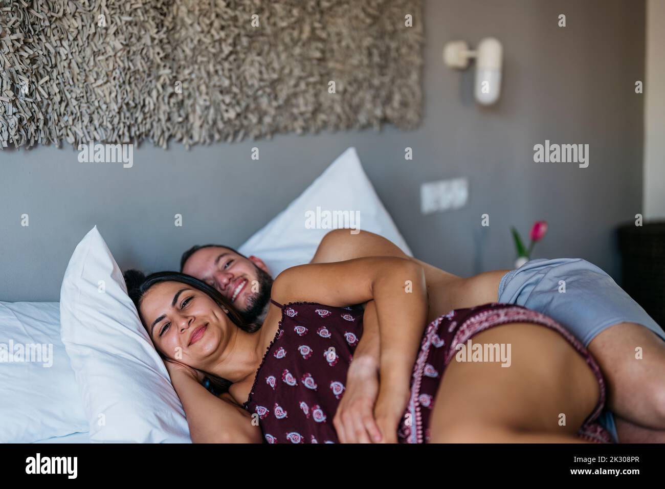 souriante mariée latine et marié regarder l'appareil photo tout en étant allongé sur un lit Banque D'Images