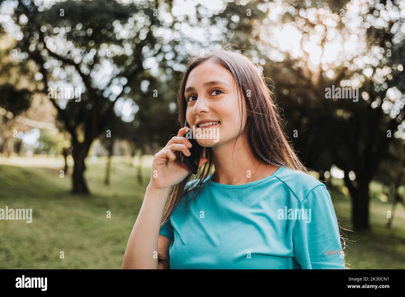 Jeune fille souriante utilisant son téléphone pour passer un appel. Communication avec les parents et les proches. Banque D'Images