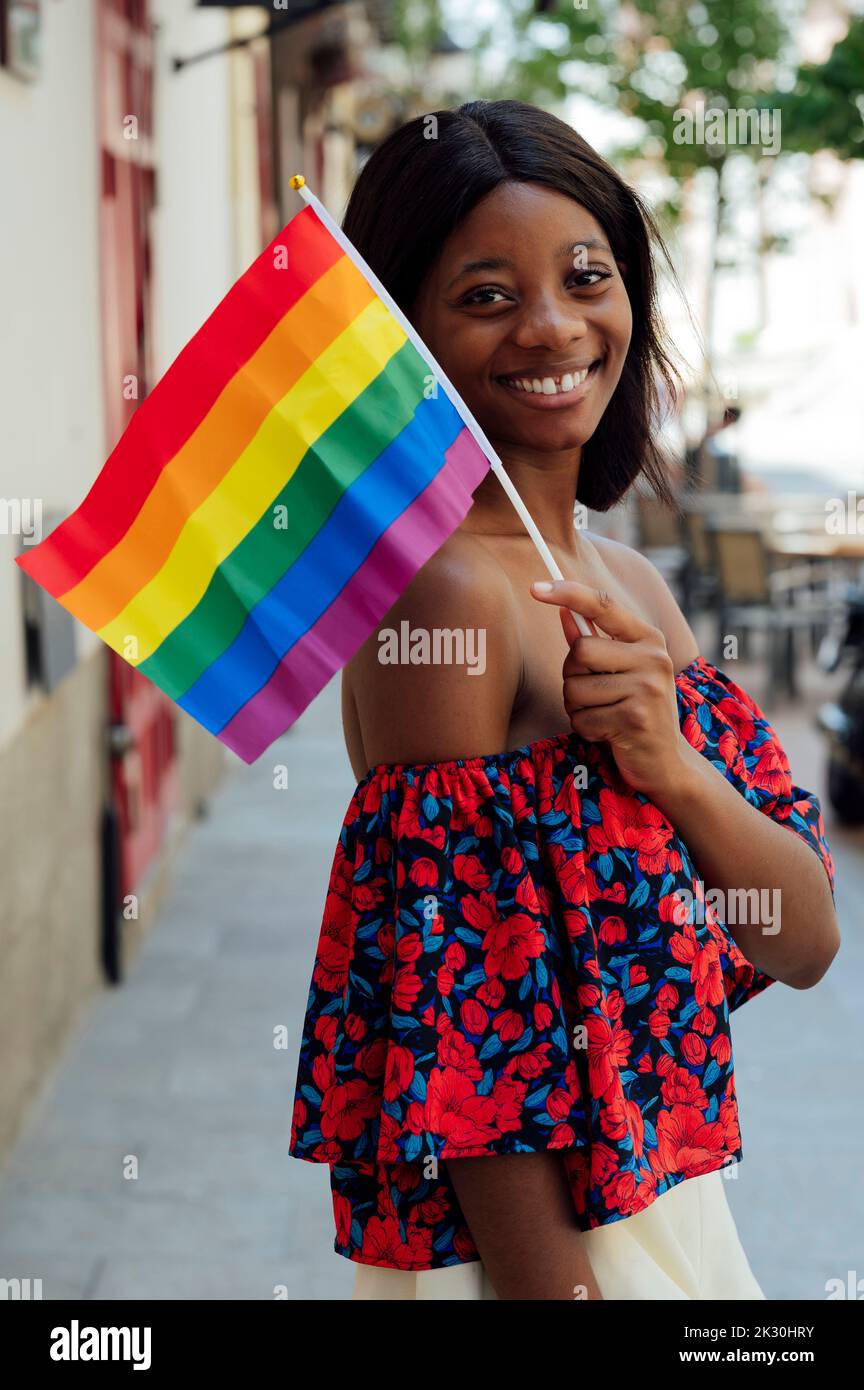 Jeune femme heureuse portant le drapeau arc-en-ciel Banque D'Images