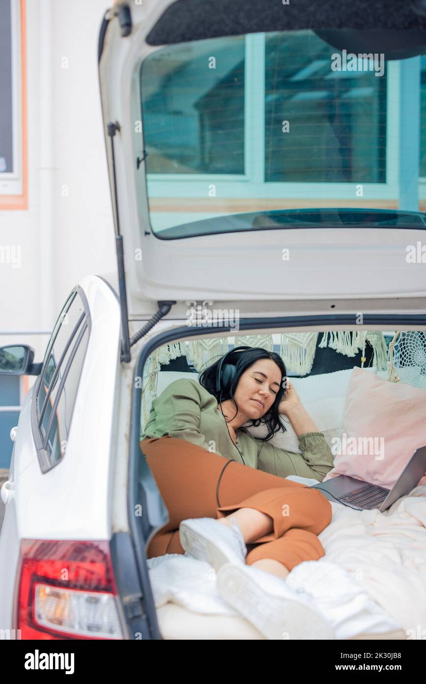 Femme portant un casque dormant dans le coffre de la voiture Banque D'Images