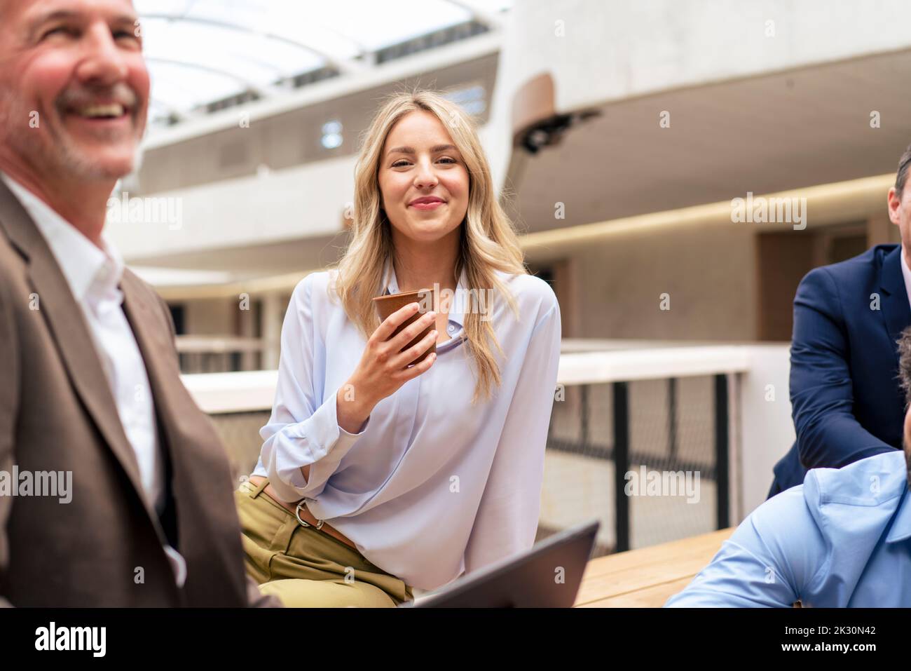 Femme d'affaires souriante prenant un café par des collègues au bureau Banque D'Images