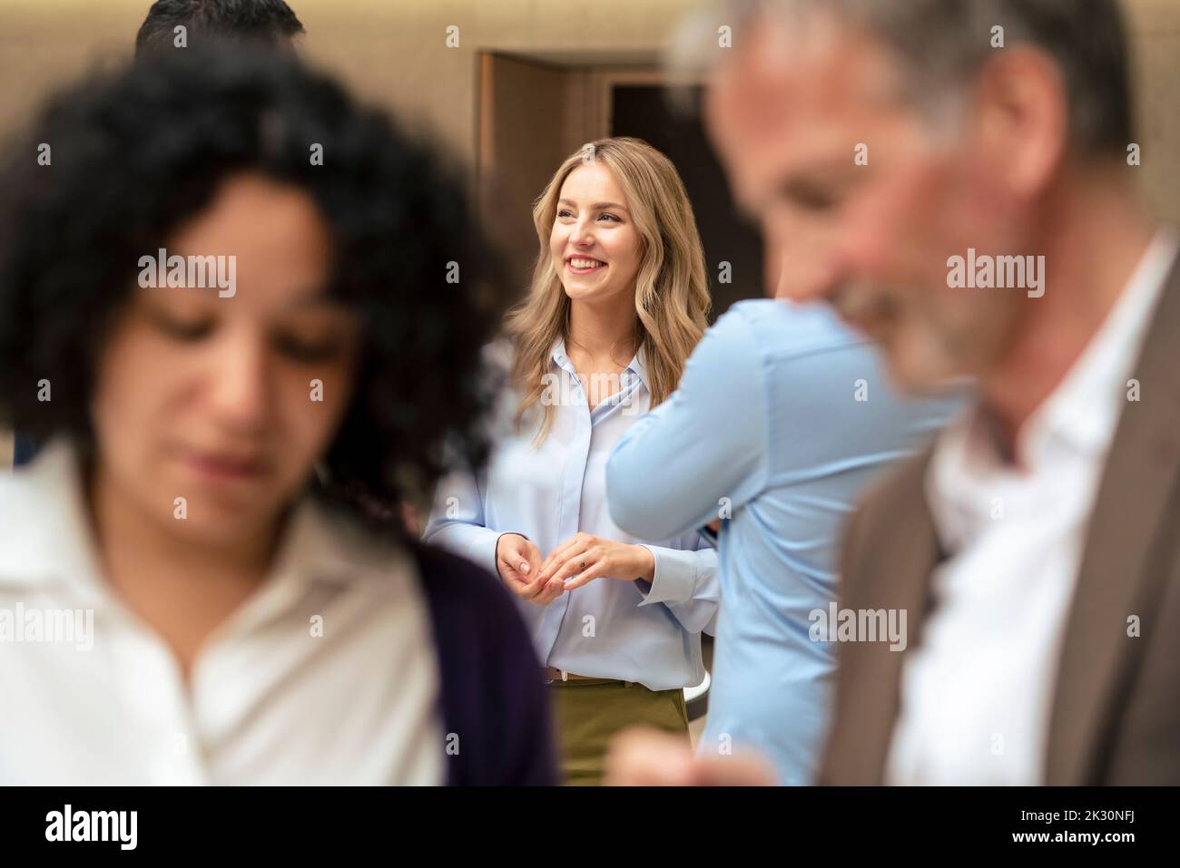 Bonne femme d'affaires blonde avec collègues au bureau Banque D'Images