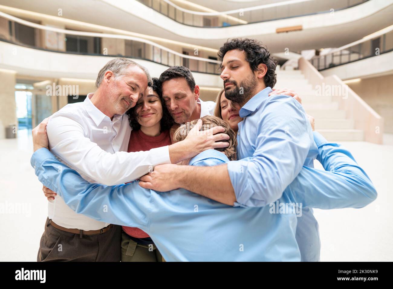 Des collègues d'affaires souriants s'embrassent les uns les autres dans le couloir Banque D'Images