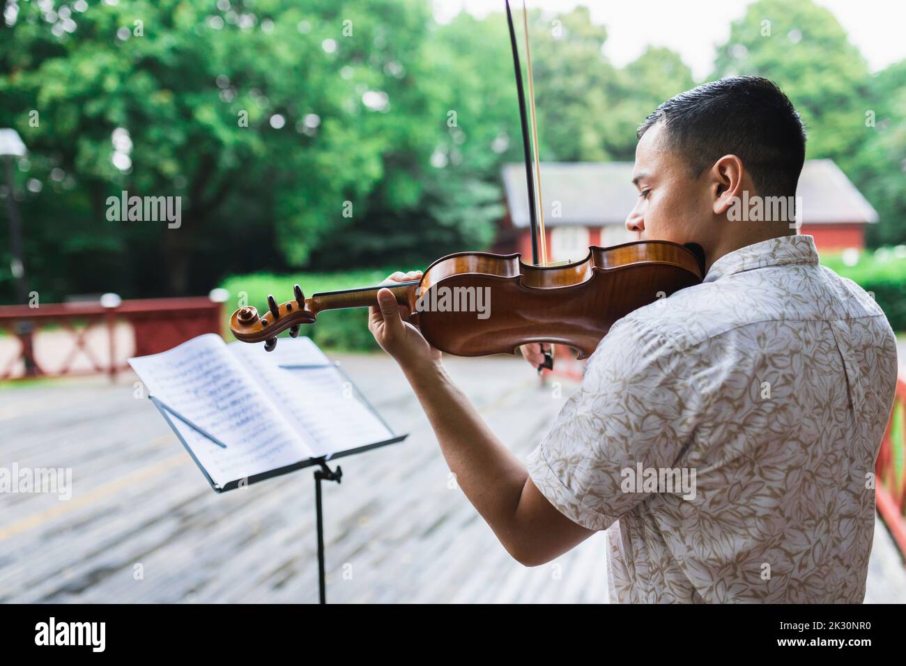Jeune violoniste jouant du violon en partitions au parc Banque D'Images