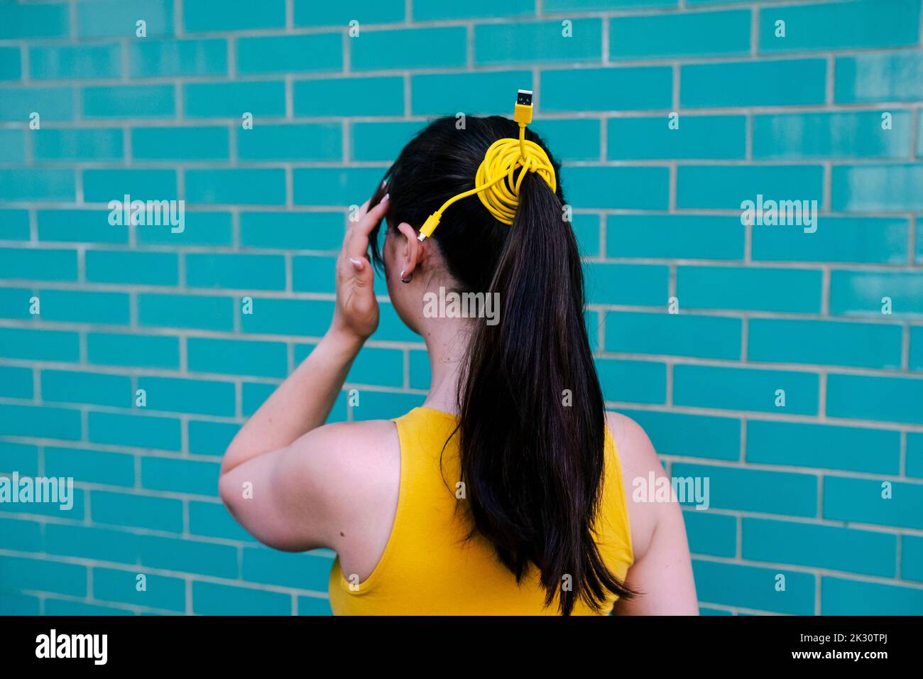 Queue de cheval de femme attachée avec le fil de câble devant le mur Banque D'Images