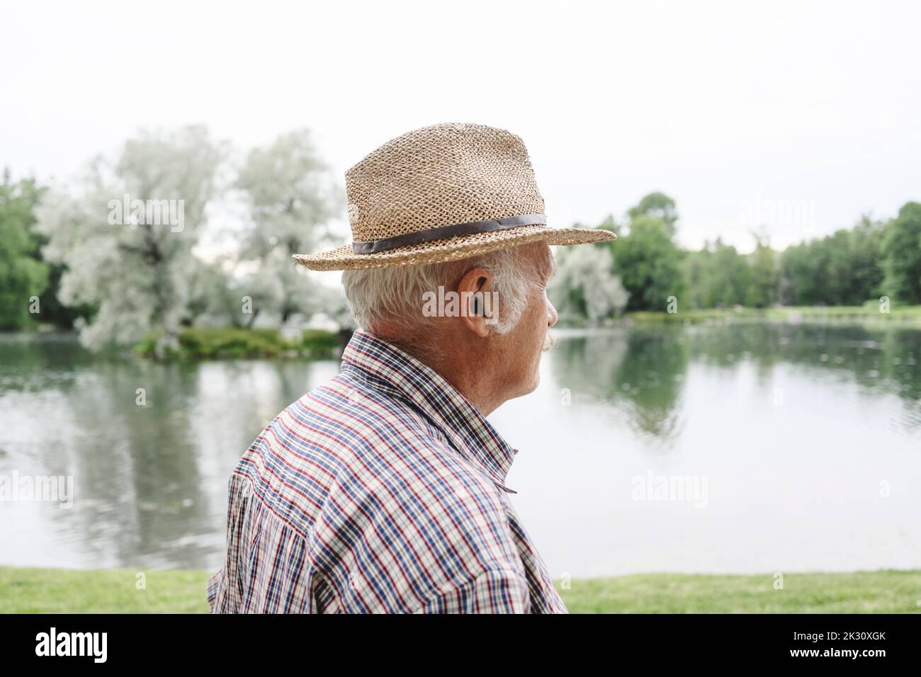 Homme âgé portant un chapeau près du lac au parc Banque D'Images