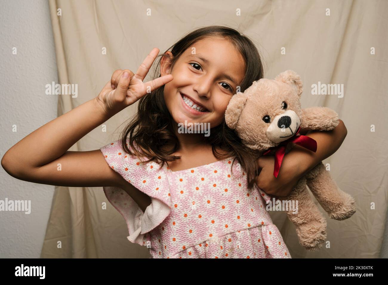 Bonne fille avec un ours en peluche signe de paix Banque D'Images