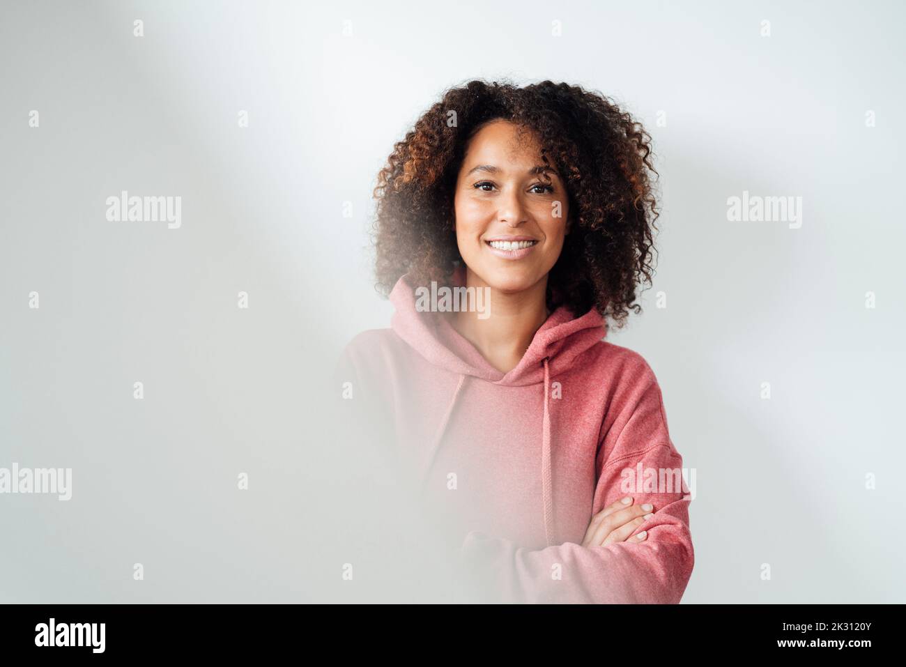 Femme mûre souriante devant le mur blanc Banque D'Images
