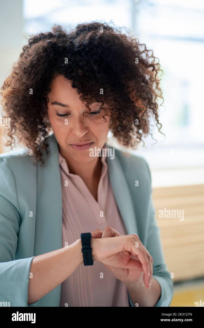Femme d'affaires mature qui vérifie son temps sur une montre intelligente Banque D'Images
