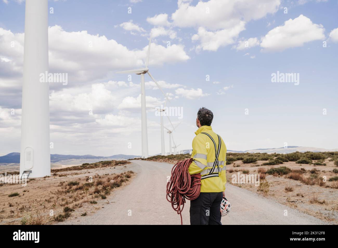 Ingénieur avec corde regardant les éoliennes à la ferme éolienne Banque D'Images