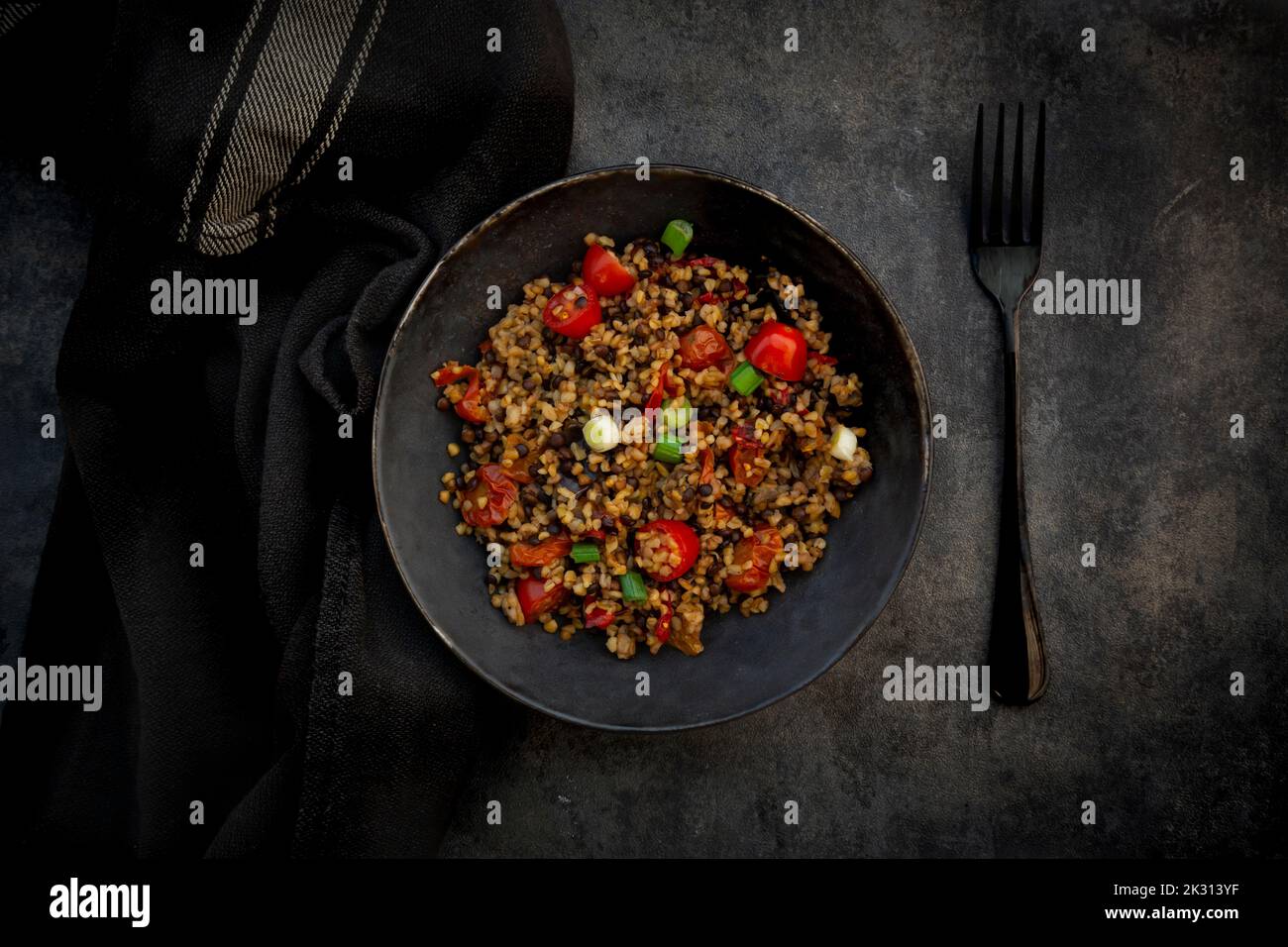Prise de vue en studio d'un bol de bulgur avec des lentilles de béluga, des tomates, des poivrons, de l'aubergine et du scallion Banque D'Images