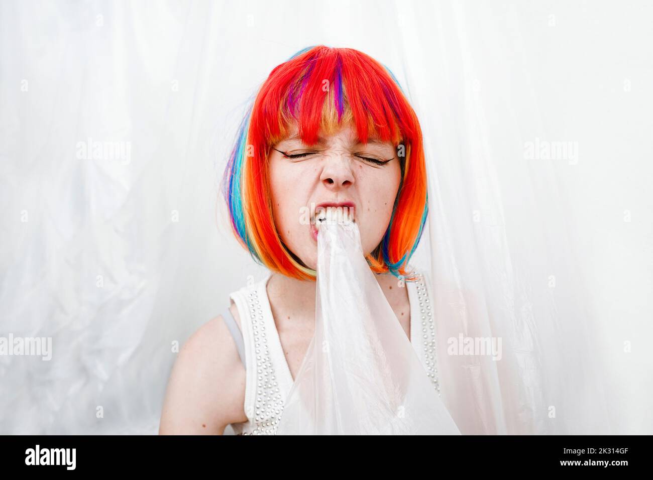 Femme en colère avec des cheveux teints multicolores piquant du plastique Banque D'Images
