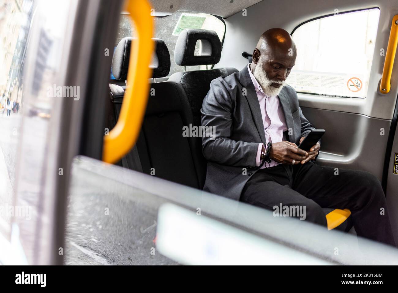 Homme d'affaires senior utilisant un téléphone portable en taxi Banque D'Images