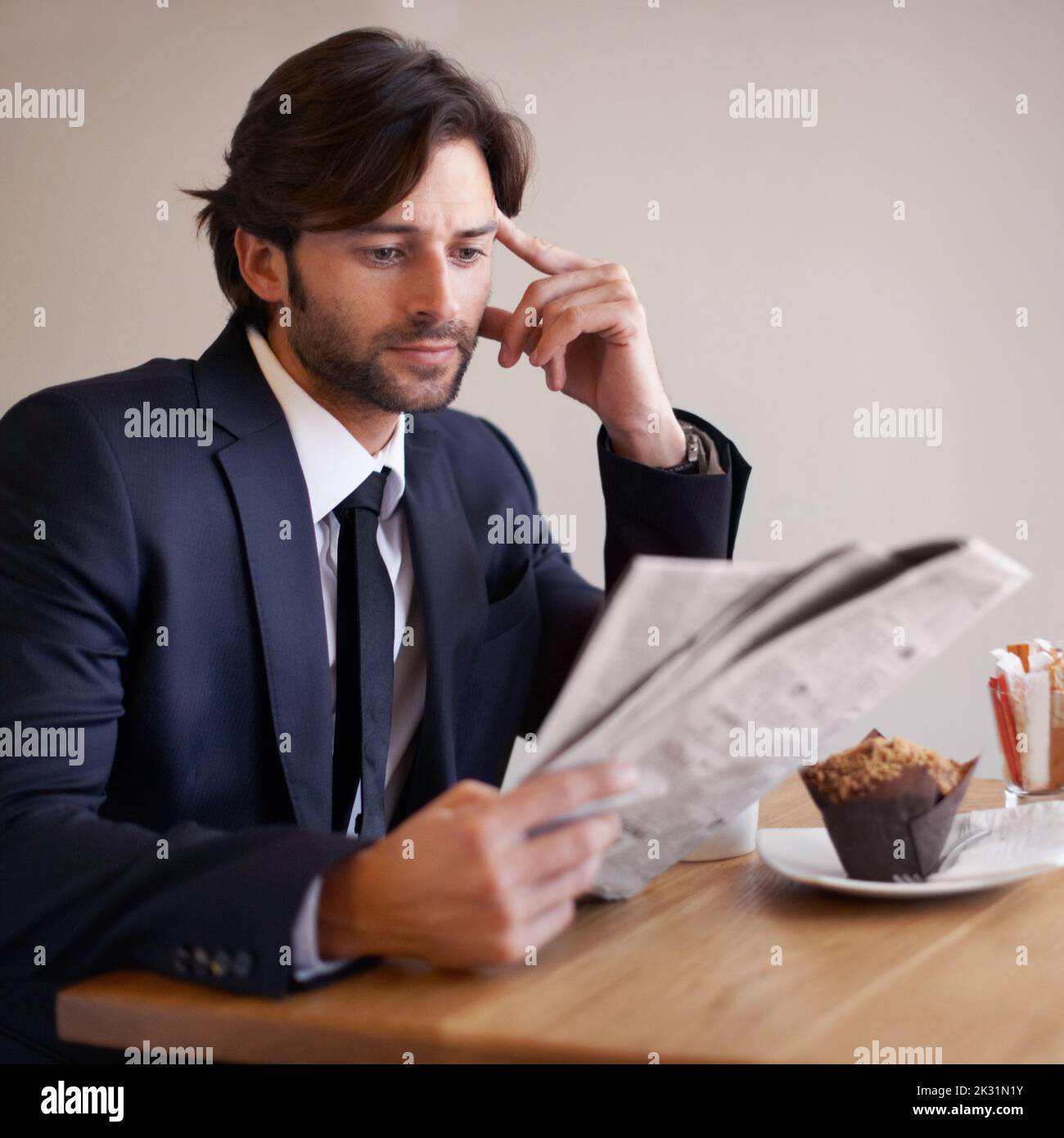 Quelle est l'actualité aujourd'hui ? Un jeune homme d'affaires assis dans un café lisant un journal. Banque D'Images