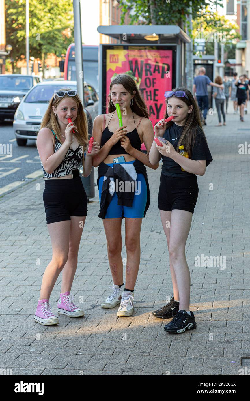 Jeunes filles mangeant de la glace dans la rue , Derry , Irlande du Nord . Banque D'Images