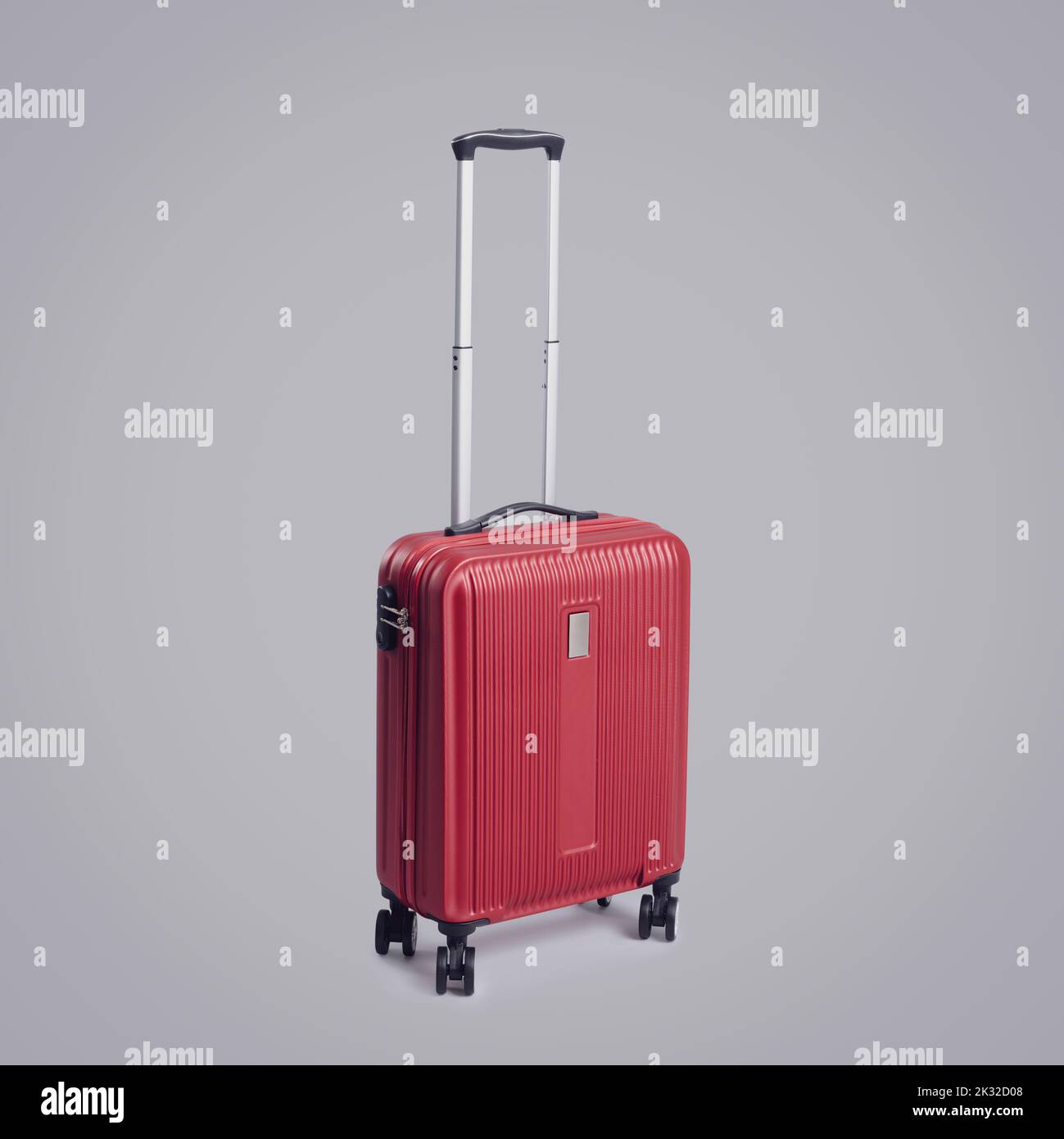 Valise à roulettes rouge élégante avec quatre roues sur fond gris, concept voyage et tourisme Banque D'Images