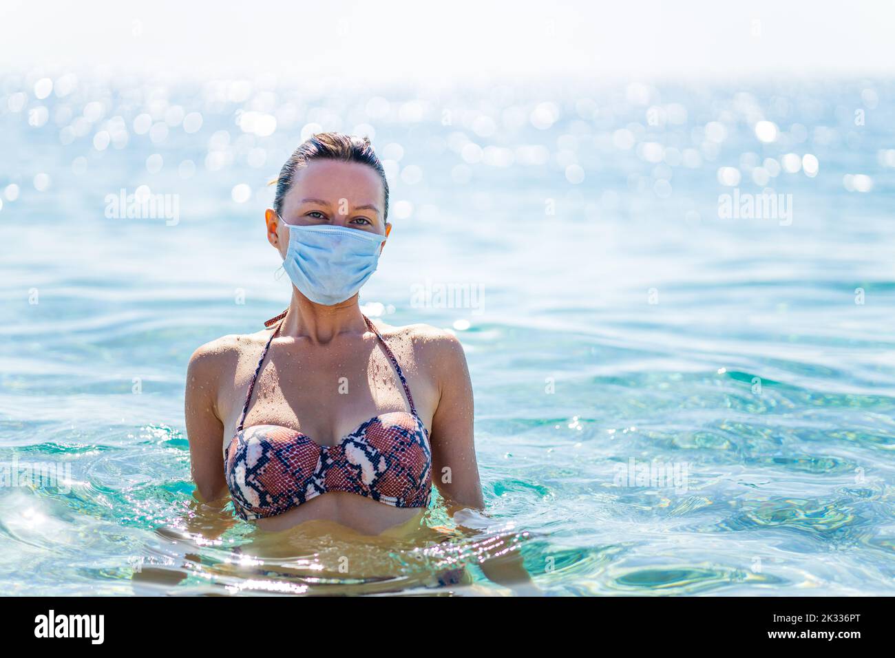 femme paranoïaque nageant sur l'eau avec un masque sur le visage le jour ensoleillé Banque D'Images